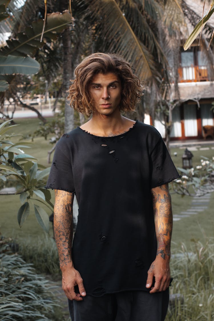 A Tattooed Man Wearing A Tattered Shirt