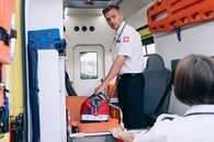 Paramedic organizing first aid kit inside an ambulance, focusing on emergency preparedness.