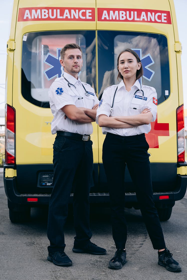 A Male And Female Paramedic Standing Beside An Ambulance