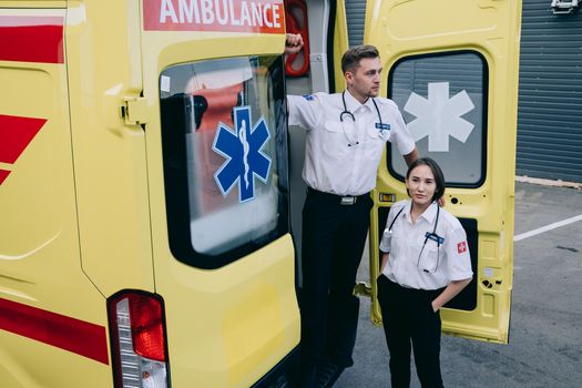Paramedics stand by a yellow ambulance, ready to assist in emergencies.