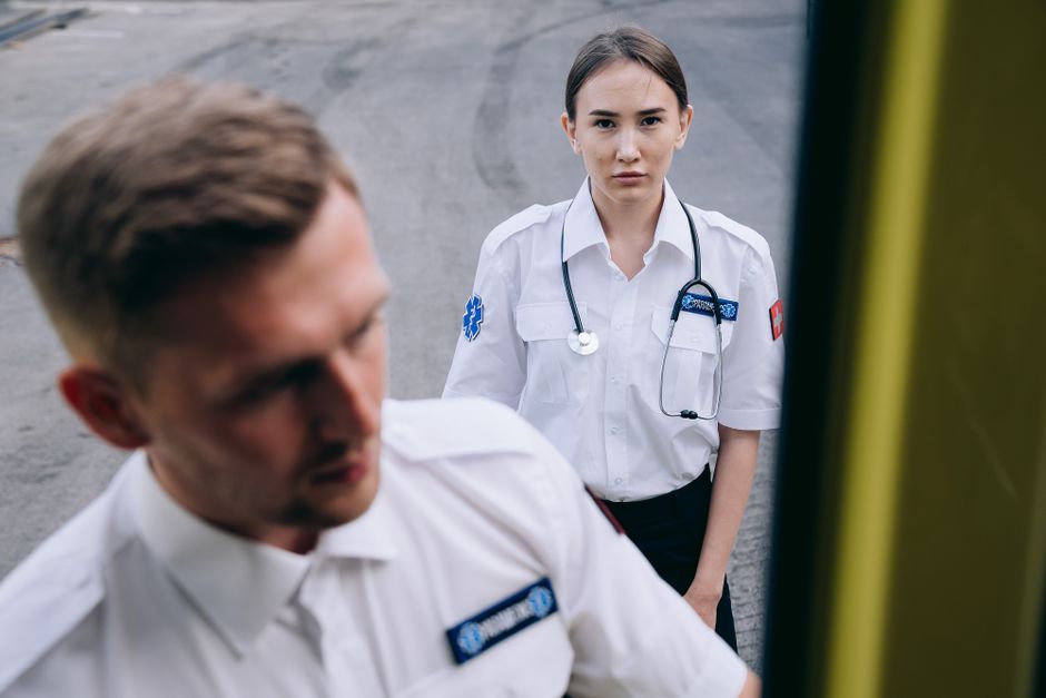 Paramedics in uniforms with stethoscope ready for an emergency response outside.