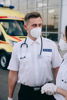 Paramedics wearing protective masks and gloves standing by an ambulance, ready to assist.