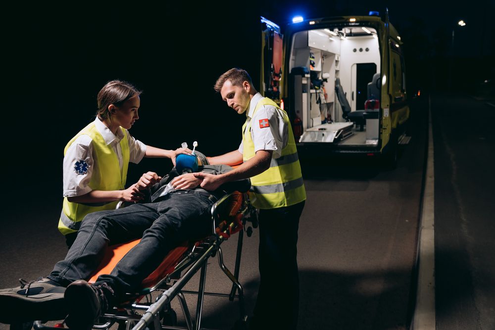 Paramédicos atendiendo a un paciente en camilla junto a la ambulancia