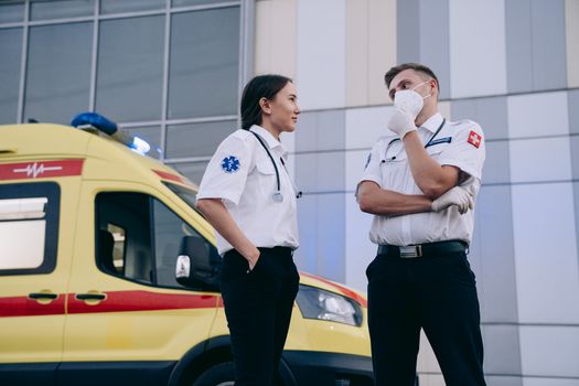 Paramedics conversing outdoors near an ambulance, highlighting teamwork in emergency medical services.