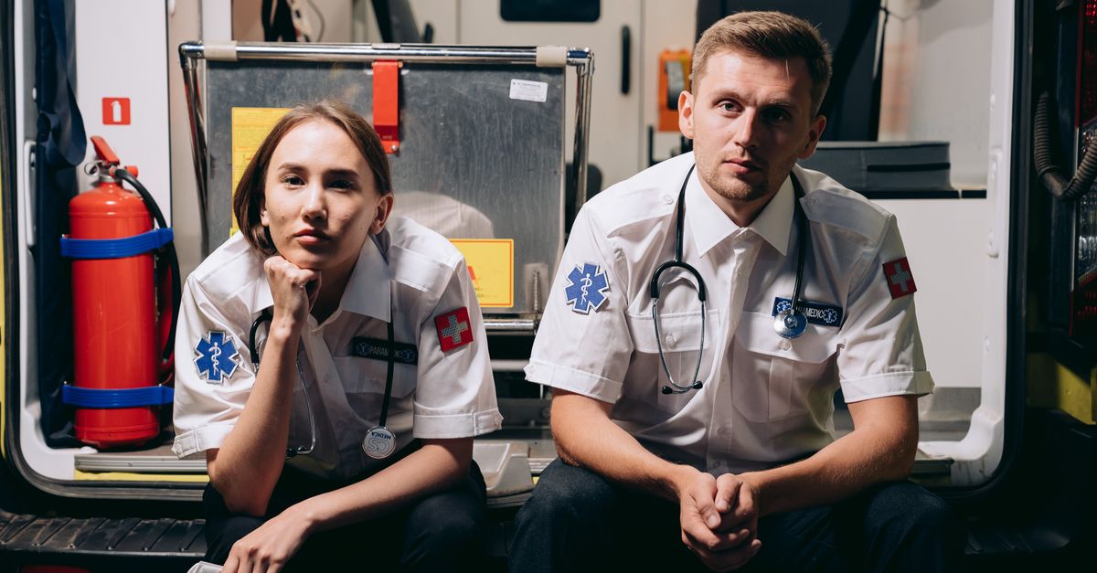 Photo by Mikhail Nilov Two paramedics in uniforms sitting inside an ambulance, showcasing teamwork and readiness.