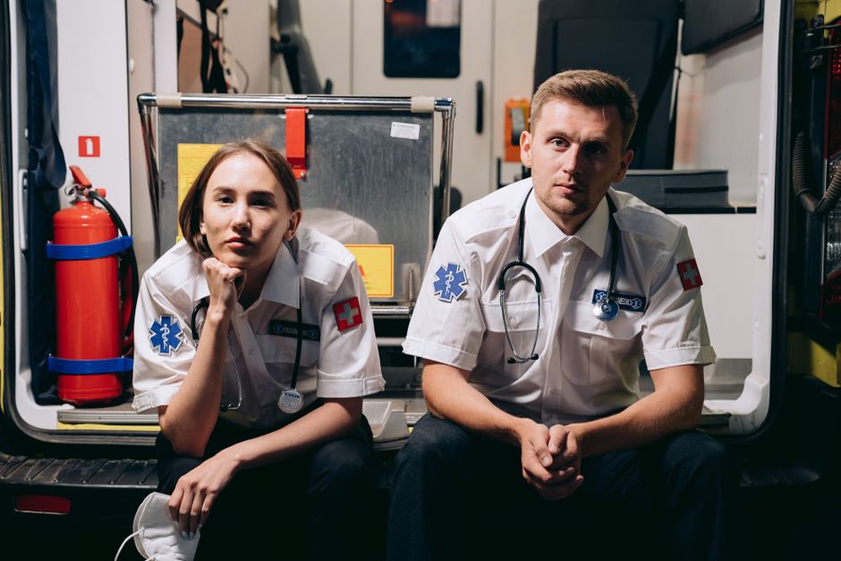 Photo by Mikhail Nilov Two paramedics in uniforms sitting inside an ambulance, showcasing teamwork and readiness.