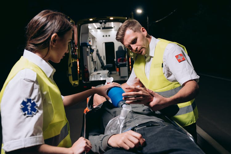 Paramedics Giving First Aid To A Person Lying On A Stretcher