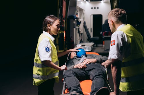 Free Paramedics Giving First Aid to a Person Lying on a Stretcher Stock Photo