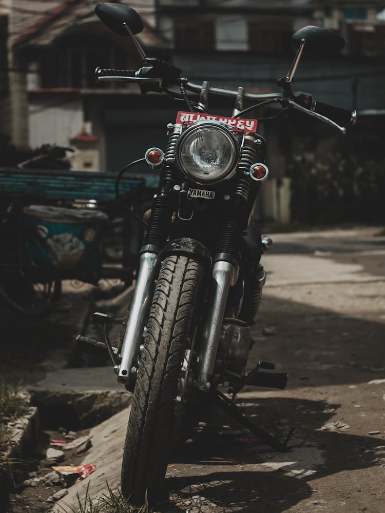 A Black Motorbike Parked Near A Street Gutter