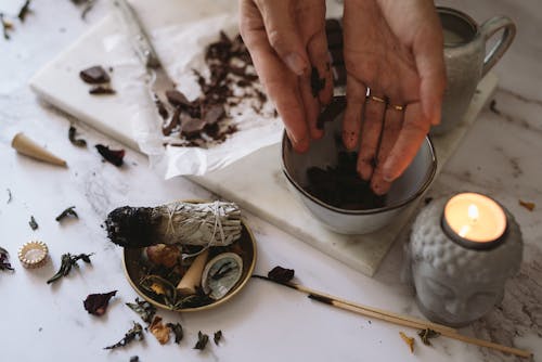 Close-up of Woman Putting Chocolate into a Mug Standing on a Table with a Candle and Incense