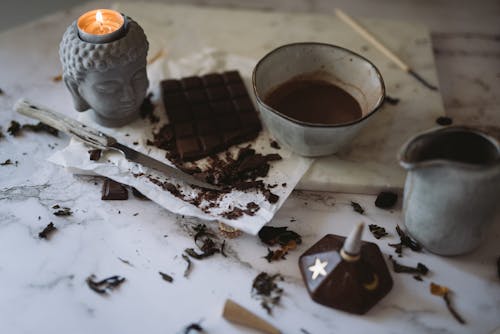 Chocolate, Candle, Mug and Pot Standing on a Table 