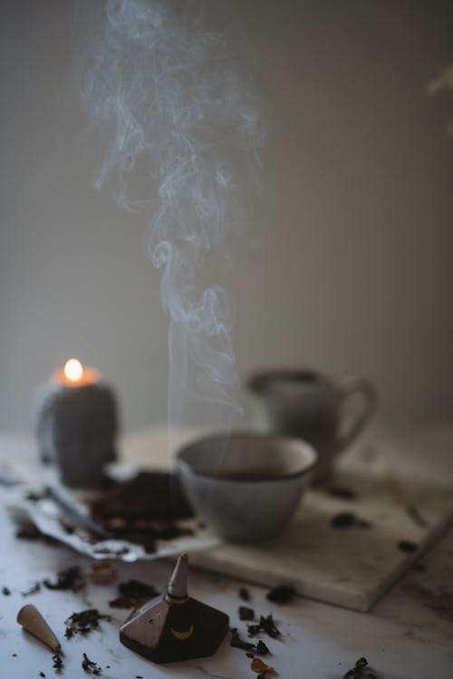 Burning Incense and Candle Standing on a Table with Ceramic Dishes 