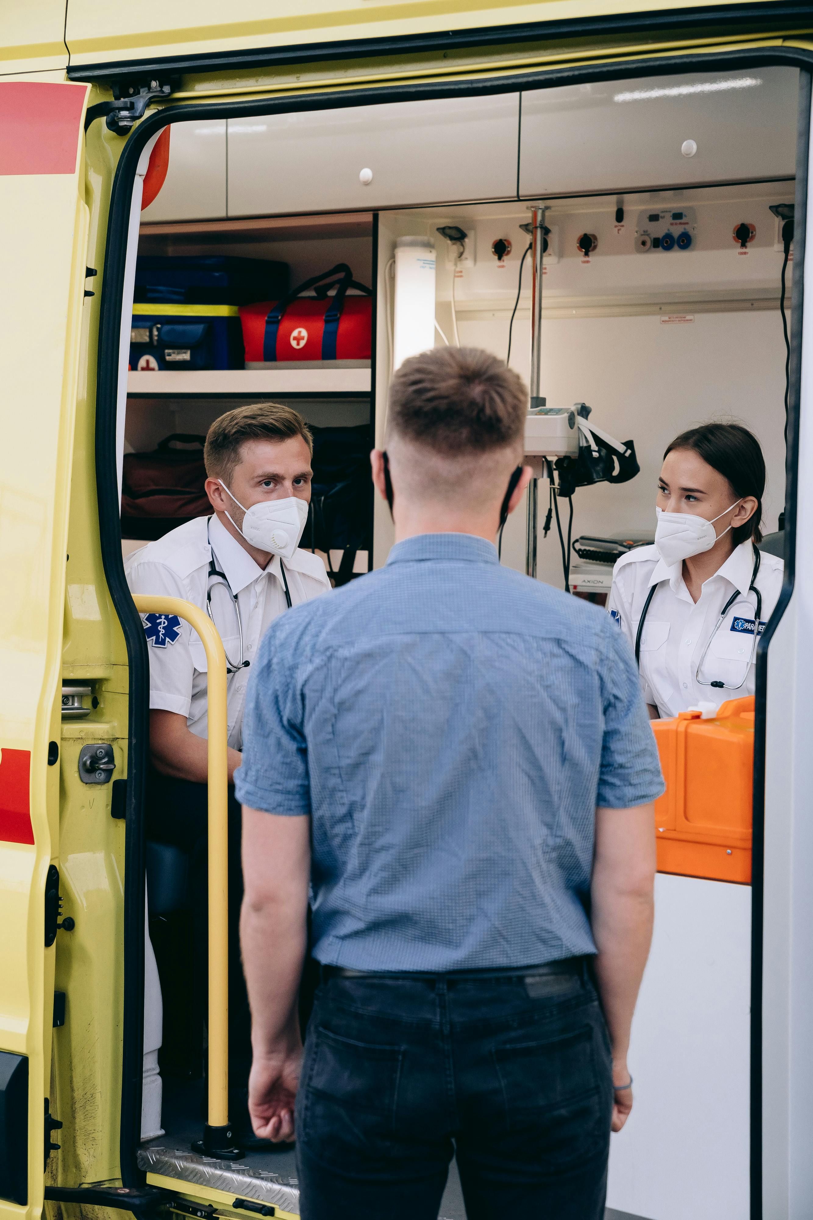 paramedics wearing face masks discussing inside an ambulance