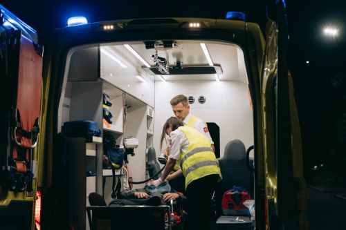 Free Paramedics attend to a patient inside an ambulance, providing emergency medical assistance at night. Stock Photo