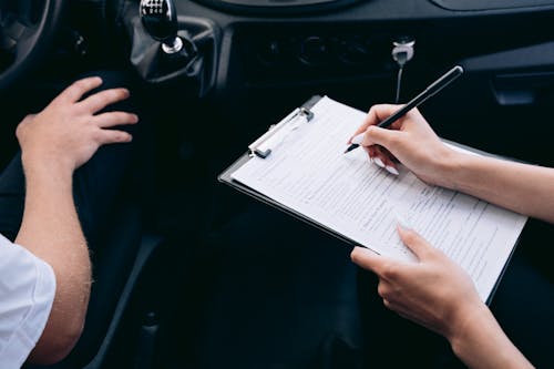 Free Person Writing on a Clipboard Inside the Vehicle Stock Photo