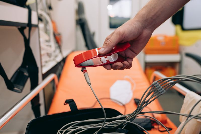 A paramedic holding medical equipment inside an ambulance, ready for emergency care.
