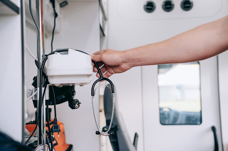 A close-up image showcasing a hand holding a stethoscope inside an ambulance, depicting medical readiness.