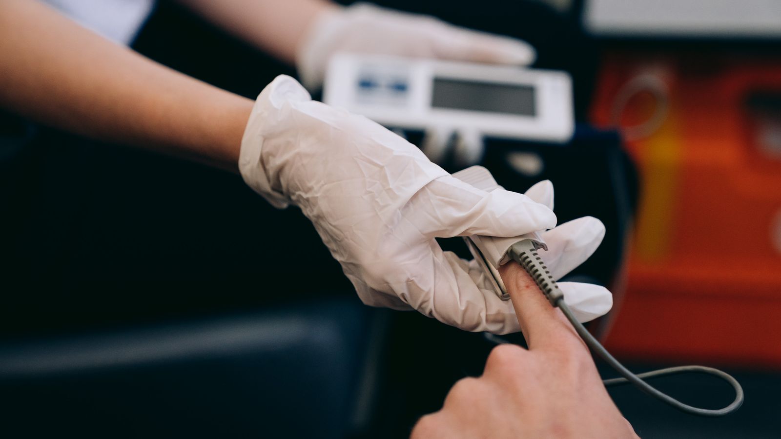 Close-up of a healthcare professional using a pulse oximeter on a patient's finger to monitor vital signs.