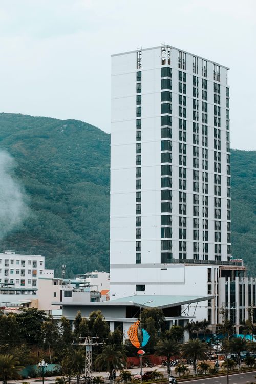 Free A tall modern building set against a lush green mountain landscape, offering urban and natural contrast. Stock Photo