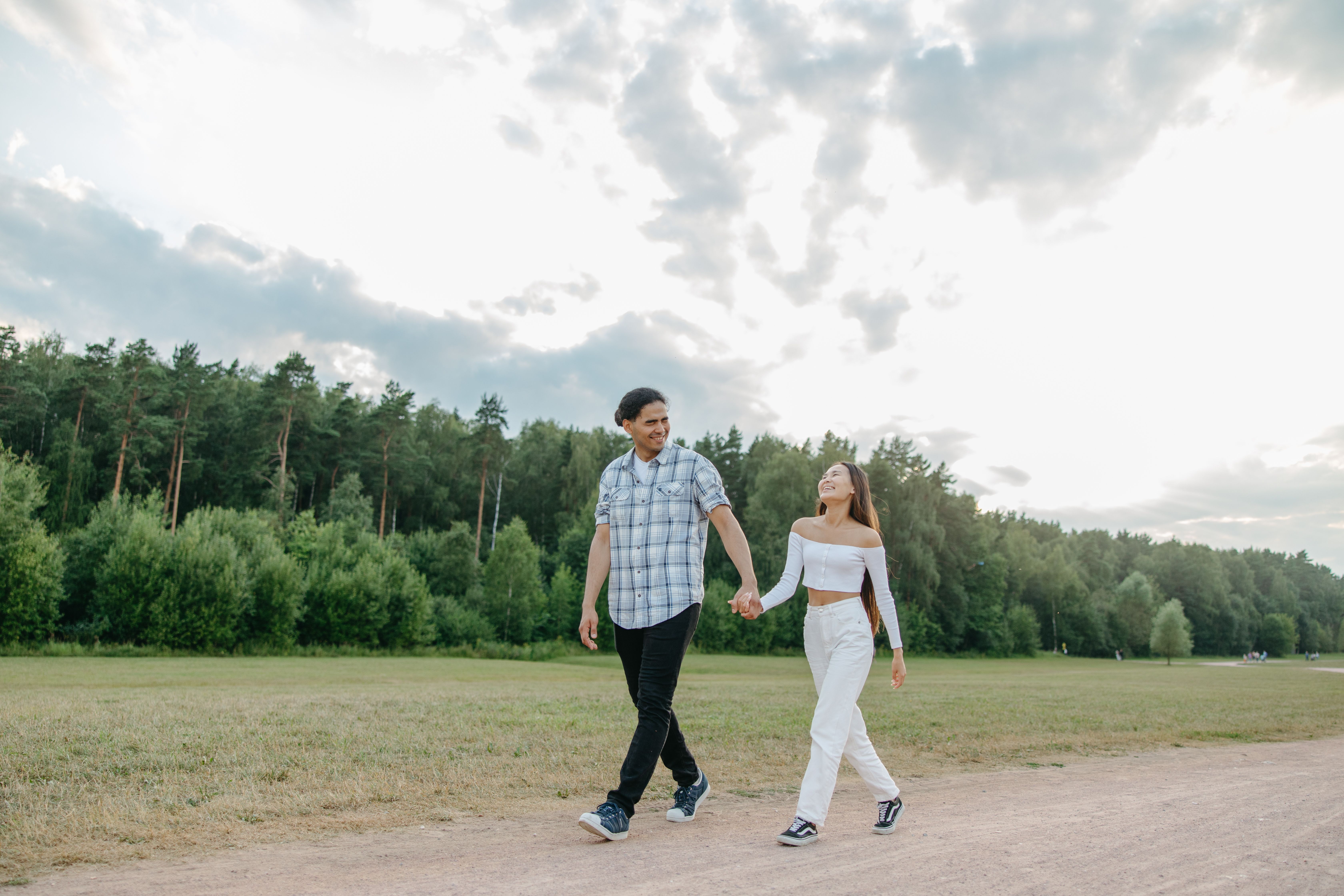 A couple enjoys a walk together on a scenic outdoor path, surrounded by lush greenery.