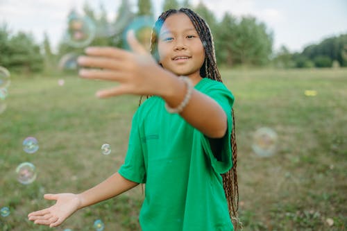 Girl in Green Shirt Playing with Soap Bubbles