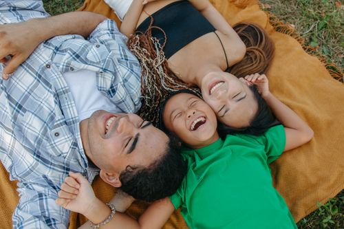 Free A happy family enjoying a sunny day together lying on a picnic blanket. Stock Photo