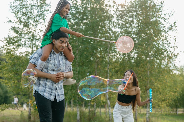 A Family Playing Bubbles In The Park