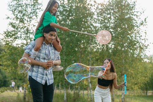 Free Family enjoying a playful day outdoors with bubbles in the park. Happy moments captured. Stock Photo