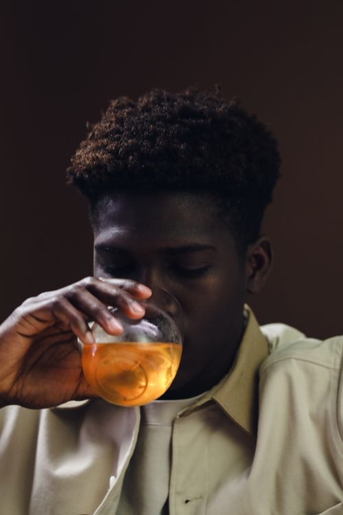 Free African American man savoring an Aperol Spritz in a cozy indoor setting. Stock Photo