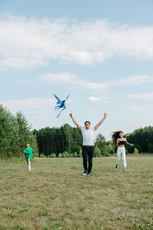 Free Dynamic family bonding while flying a kite in an open grassy park, full of joy and laughter. Stock Photo