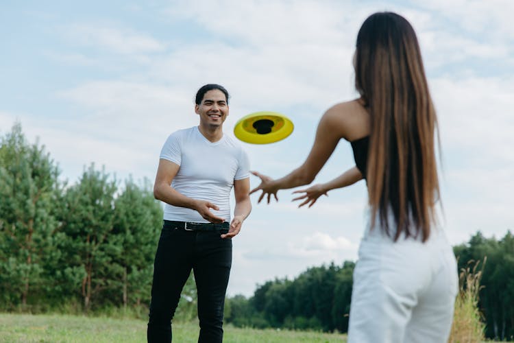 A Couple Playing Frisbee In The Park