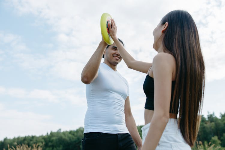 A Man And A Woman Holding A Yellow Frisbee