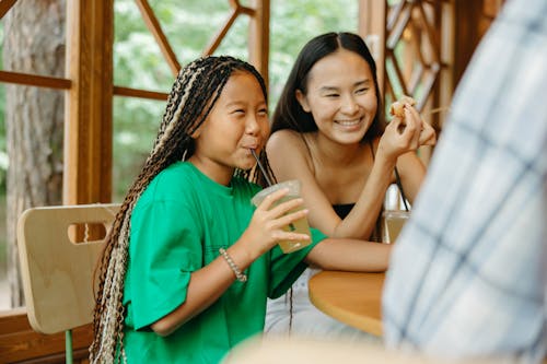 A Young Girl Sipping a Drink while Smiling