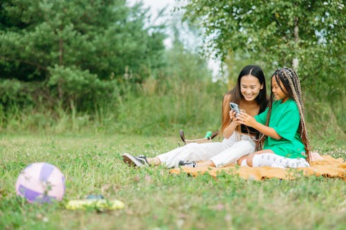 Woman and a Girl Looking at the Screen of a Cellphone