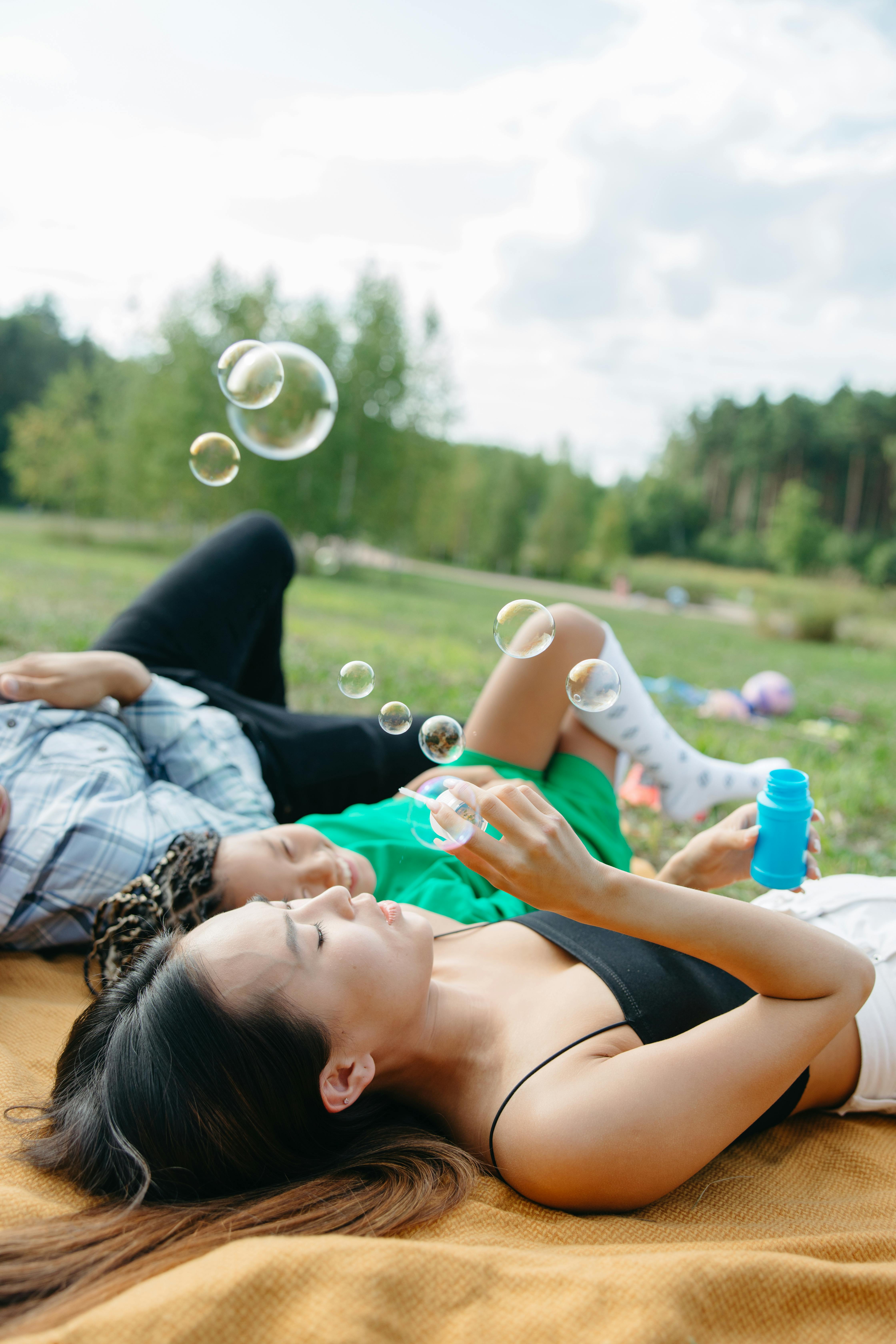 a woman and a young girl lying while playing bubbles