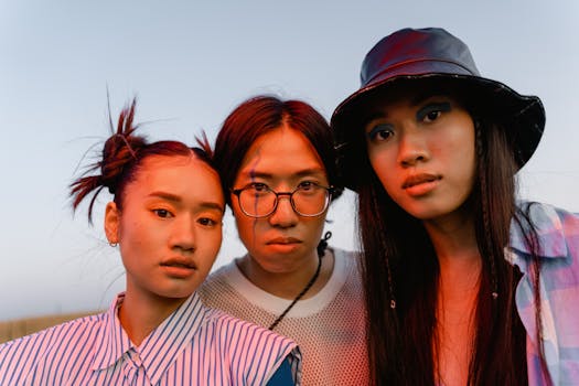 Three fashionable young adults posing outdoors at sunset, showcasing diverse styles and accessories.