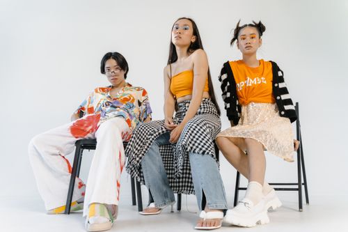 Free Three stylish teens pose confidently in bright, modern attire in a studio setting. Stock Photo