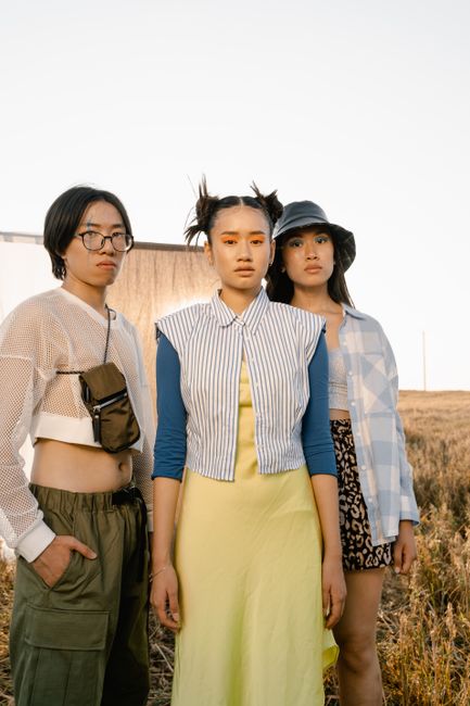 Three fashion-forward teenagers posing stylishly outdoors during sunset.