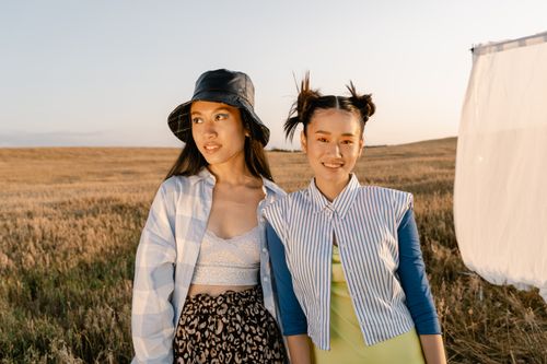Free Two fashionable young women pose in a wheat field, showcasing modern style and summer vibes. Stock Photo