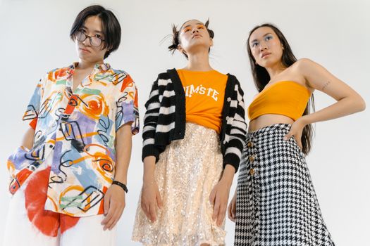 Three stylish young individuals posing confidently in a modern studio setup.