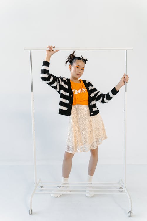 Woman in Cardigan and Lace Skirt Holding on Clothes Rack