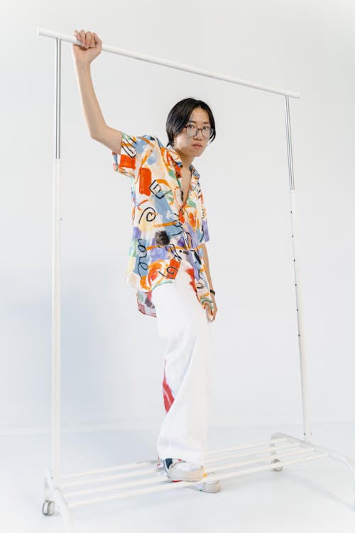 Man in Colorful Shirt Holding on Cloths Rack