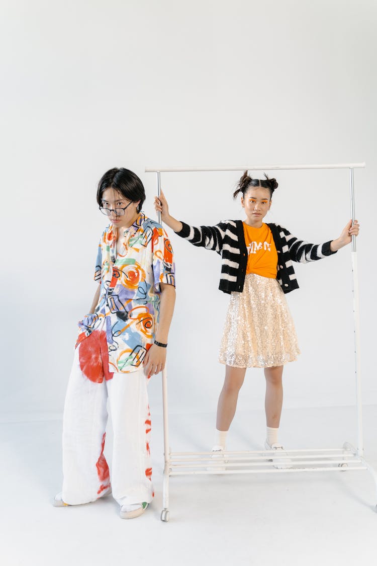 A Girl And A Boy Posing With A Clothes Rack