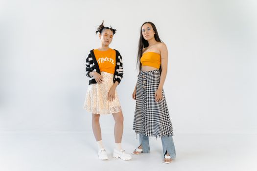 Asian women in fashionable street wear posing in a studio.