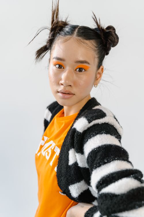 Free Portrait of a stylish woman with bold orange makeup and striped sweater in a studio. Stock Photo