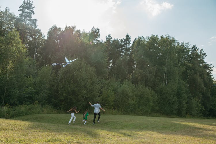 Family Running On Green Grass Field