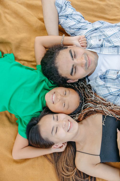 Free A joyful Asian family lying on a brown blanket, smiling peacefully together. Stock Photo