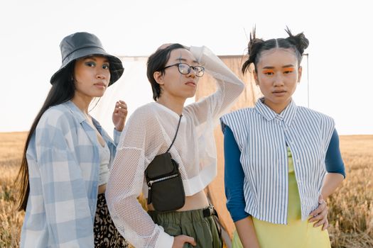 Three young adults showcase unique and bold fashion styles outdoors, blending modern aesthetics with vibrant colors.