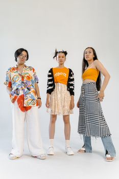 Three stylish Asian models posing in diverse outfits against a white backdrop.