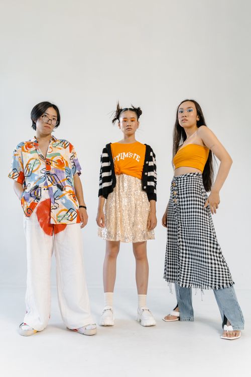 Free Three stylish Asian models posing in diverse outfits against a white backdrop. Stock Photo